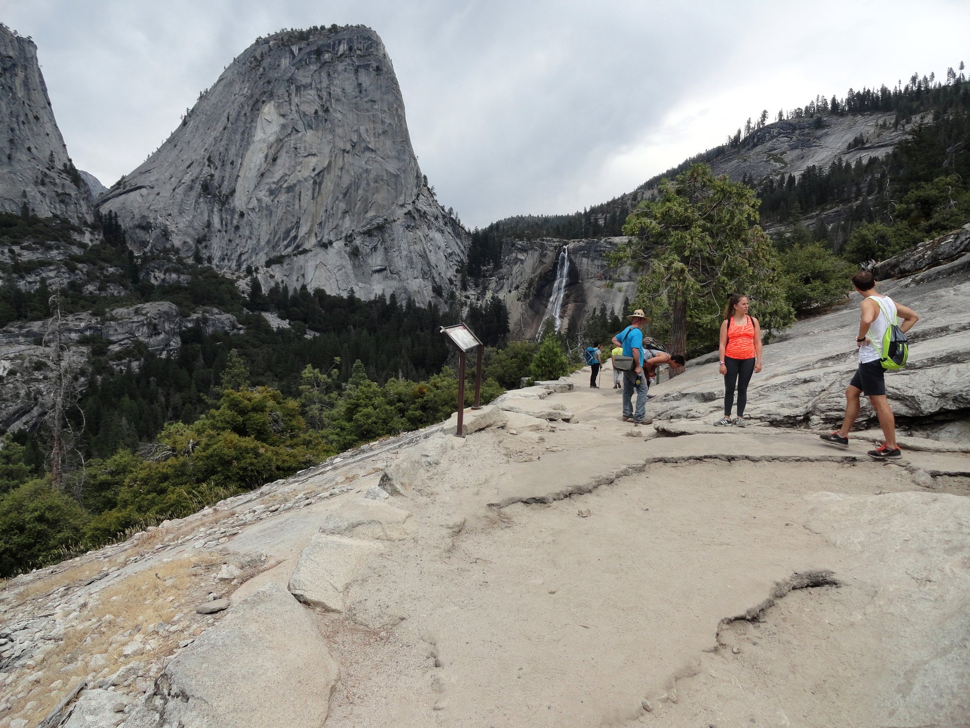 Hikers pause along the John Muir Trail in Yosemite National Park, with granite peaks, Nevada Fall, and the Sierra Nevada backcountry in view